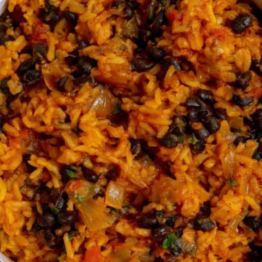 A bowl of black beans and rice garnished with fresh herbs