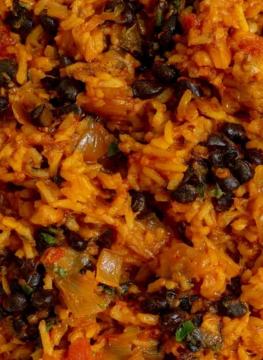 A bowl of black beans and rice garnished with fresh herbs