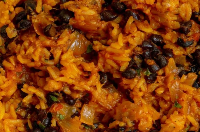 A bowl of black beans and rice garnished with fresh herbs