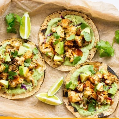 Cauliflower tacos topped with avocado cream sauce on a white plate