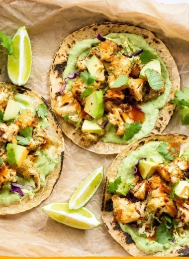 Cauliflower tacos topped with avocado cream sauce on a white plate