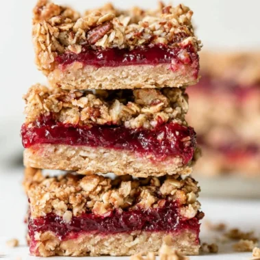 Cozy cranberry sauce oat bars topped with a sprinkle of oats and cranberries