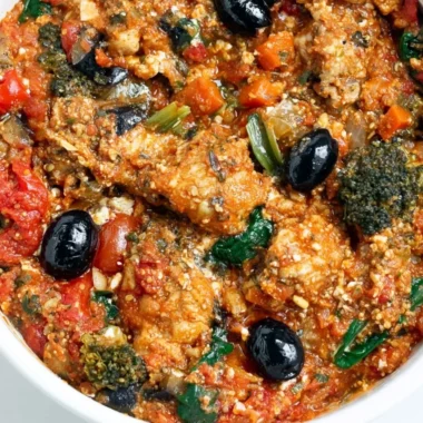 Plate of cozy Mediterranean chicken garnished with herbs and served with vegetables.