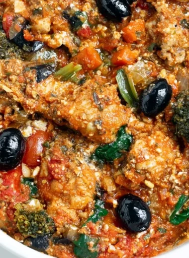 Plate of cozy Mediterranean chicken garnished with herbs and served with vegetables.