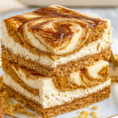 Cozy pumpkin cheesecake bars topped with whipped cream and a sprinkle of cinnamon