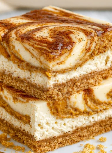 Cozy pumpkin cheesecake bars topped with whipped cream and a sprinkle of cinnamon