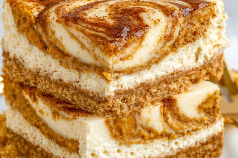 Cozy pumpkin cheesecake bars topped with whipped cream and a sprinkle of cinnamon