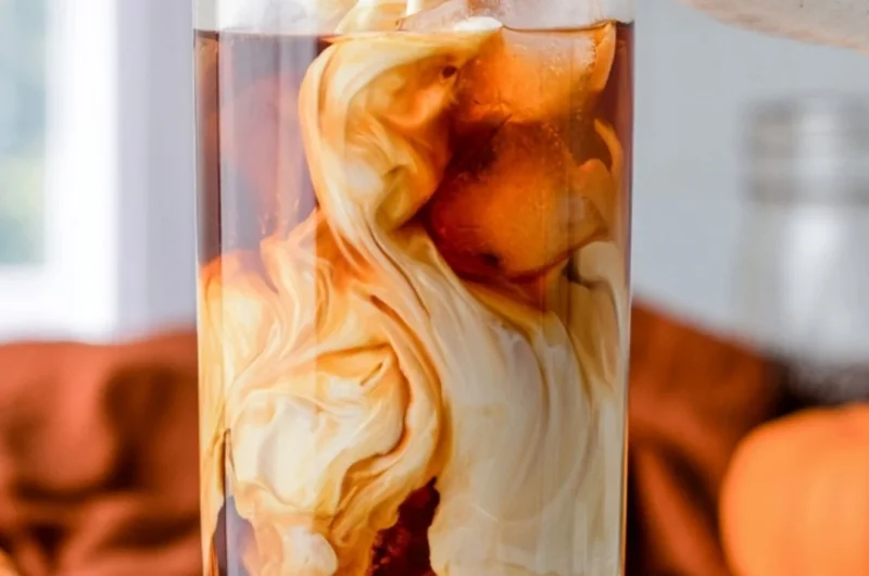 Cozy pumpkin spice cold brew served in a glass with autumn leaves
