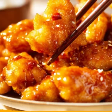 Crispy orange chicken served with fresh vegetables and garnished