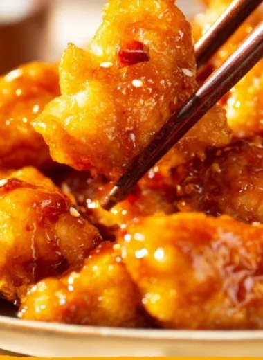 Crispy orange chicken served with fresh vegetables and garnished