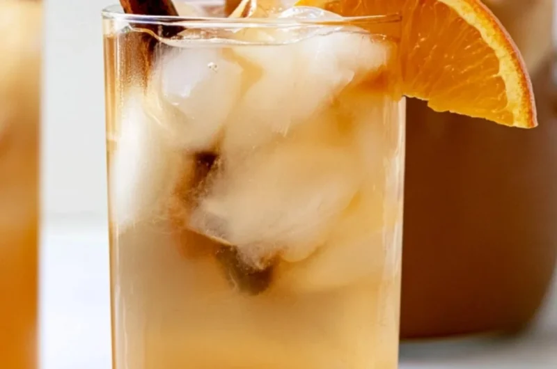 Delicious fall harvest punch in a decorative glass with autumn fruits.
