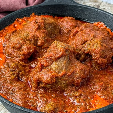 Bowl of delicious Nigerian beef stew served with rice and plantains