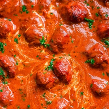 Delicious bowl of cozy chicken tikka masala garnished with cilantro and served with rice.