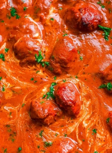 Delicious bowl of cozy chicken tikka masala garnished with cilantro and served with rice.