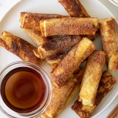 Delicious French Toast Roll-Ups served with syrup and strawberries