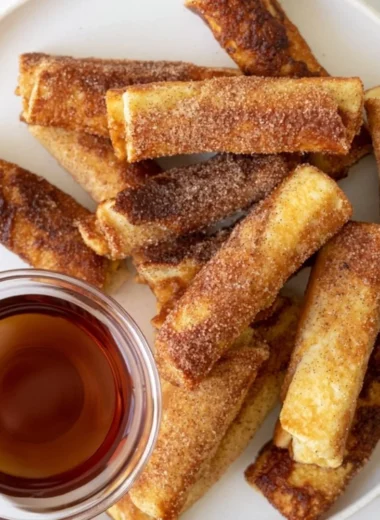 Delicious French Toast Roll-Ups served with syrup and strawberries