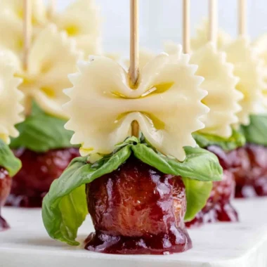 Bowtie pasta served with cocktail meatball skewers on a platter.