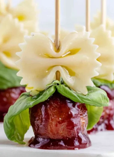 Bowtie pasta served with cocktail meatball skewers on a platter.