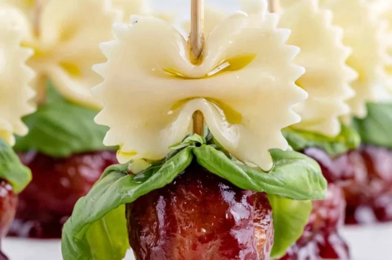 Bowtie pasta served with cocktail meatball skewers on a platter.