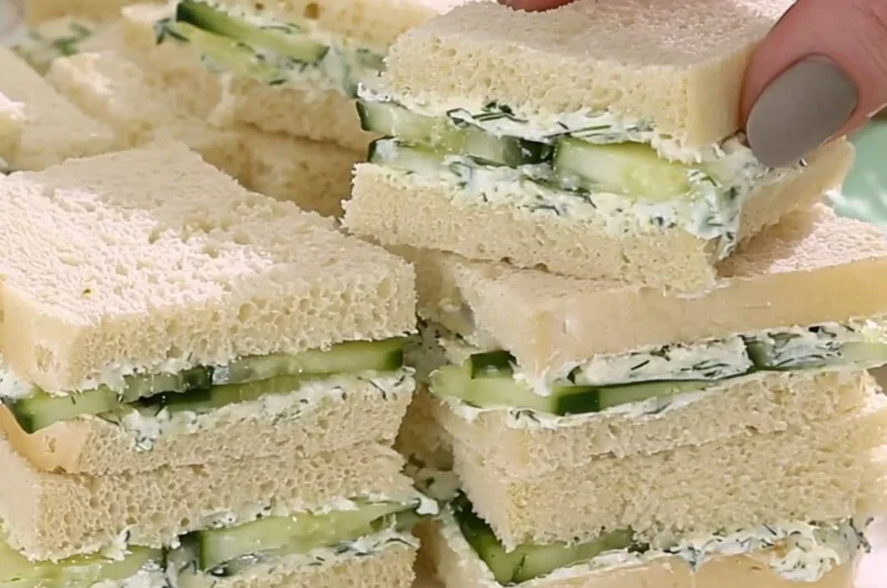 Plate of cucumber sandwiches with fresh herbs and a side of tea