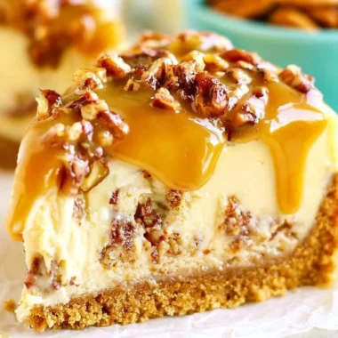 Slice of delectable Pecan Praline Cheesecake topped with pecans and caramel sauce