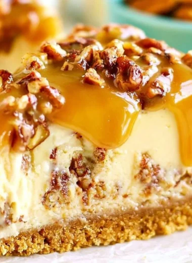 Slice of delectable Pecan Praline Cheesecake topped with pecans and caramel sauce