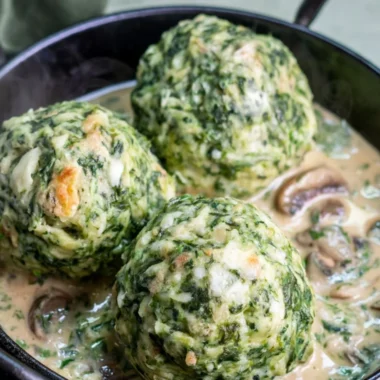 Plate of spinach dumplings served with creamy mushroom sauce
